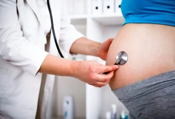 Médica examina a barriga de uma gestante com o estetoscópio