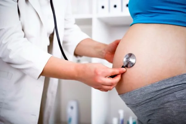 Médica examina a barriga de uma gestante com o estetoscópio