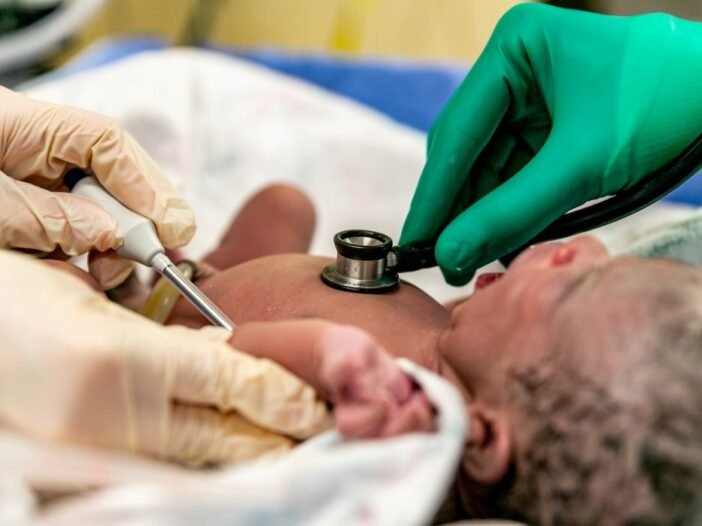 O momento da expulsão do bebê no parto - Imagem de um recém nascido sendo examinado na maternidade